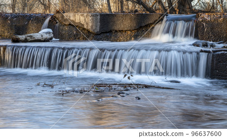 Water cascading over a river diversion dam 96637600