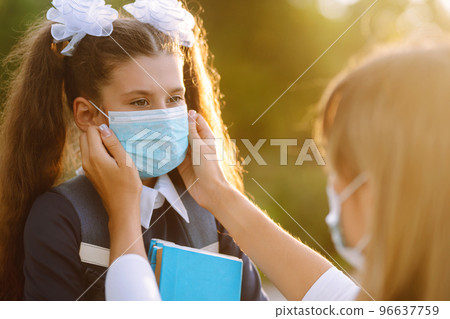 Little girl and mom in medical mask during covid-19 at sunset. Virus, pandemic, outbreak and epidemic. Little girl and mom in medical mask during covid-19 at sunset. Virus, pandemic, outbreak and epidemic. 96637759