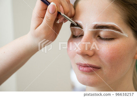 The master draws the shape of the eyebrows with white paint before coloring. The master draws the shape of the eyebrows with white paint before coloring. 96638257
