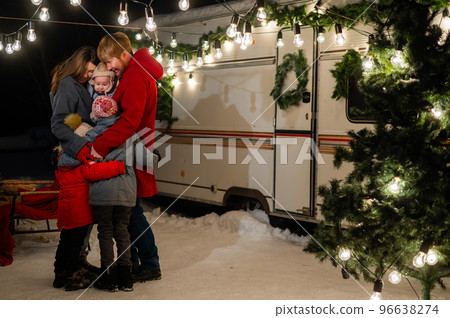Happy caucasian family hugging outdoors. Christmas decorations. Parents and three sons travel in a camper.  96638274