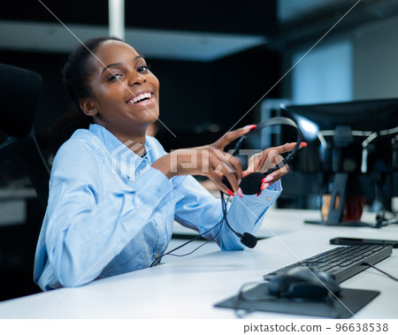 African young woman smiling and holding a headset in her hands. Call center employee.  African young woman smiling and holding a headset in her hands. Call center employee.  96638538