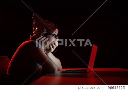 Paranoid caucasian woman typing on a computer wearing a tinfoil cap. Conspiracy theory. 96638615