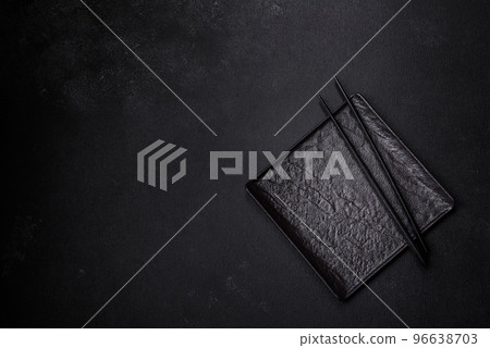 Empty plate with wooden sticks for Asian food on a dark concrete background Empty plate with wooden sticks for Asian food on a dark concrete background 96638703