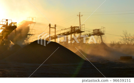 Mining quarry. Crushing plant in granite quarry at sunset dawn. Crusher in quarry. Lot of dust. Stone crushing. Industrial production of gravel. Gravel conveyor. Cone type rock crusher, shining sun Mining quarry. Crushing plant in granite quarry at sunset dawn. Crusher in quarry. Lot of dust. Stone crushing. Industrial production of gravel. Gravel conveyor. Cone type rock crusher, shining sun 96639151