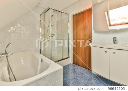 Sinks with mirrors and clean bathtub located near shower box with glass door in modern bathroom with white tiled walls 96639603