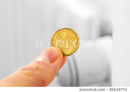 European coin in hand against the background of a hot central heating radiator. Global energy crisis concept. Expensive gas price idea 96639754