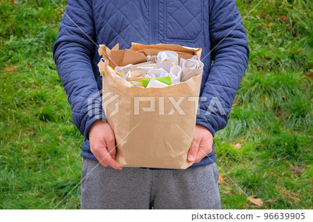 Paper and cardboard prepared for recycling. Bundles of cardboard to be recycled. Man holds a package of paper and cardboard in his hand for recycling. 96639905