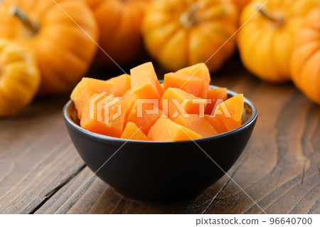 Bowl of chopped pumpkin pulp on kitchen table. Pumpkins in background. Bowl of chopped pumpkin pulp on kitchen table. Pumpkins in background. 96640700