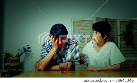 A middle man with his head down at home and a middle woman comforting him A middle man with his head down at home and a middle woman comforting him 96643349