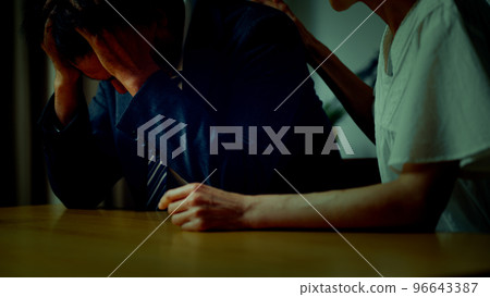 A middle man with his head down at home and a middle woman comforting him 96643387