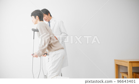 A middle-aged woman walking on crutches while being assisted by a doctor Rehabilitation image 96643401