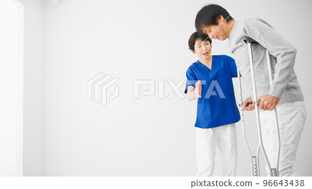 一名中年男子在醫生的幫助下拄著拐杖行走 康復圖片 96643438