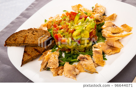 Salad guacamole with fresh tomatoes and arugula served with trout fillet Salad guacamole with fresh tomatoes and arugula served with trout fillet 96644071
