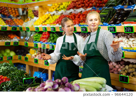 Grocery store employee points hand to young trainee girl 96644120