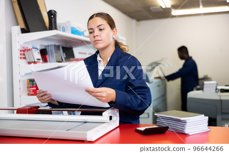 Portrait of an attentive woman checking quality of printing in printing house Portrait of an attentive woman checking quality of printing in printing house 96644266