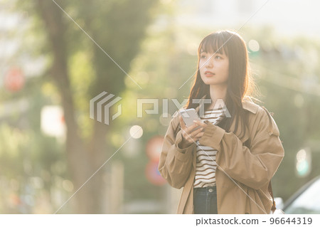 A young woman operating a smartphone outdoors A young woman operating a smartphone outdoors 96644319