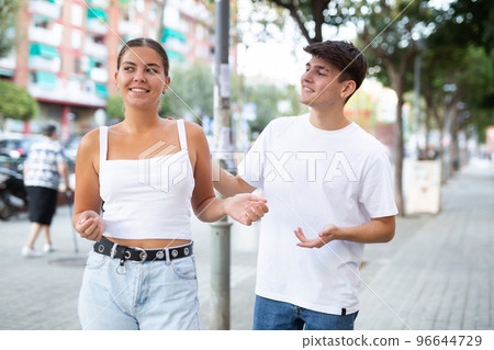Cheerful guy trying to pick up young stranger girl on city street Cheerful guy trying to pick up young stranger girl on city street 96644729