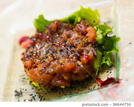 Image of salmon tartar with avocado and salad on glass plate 96644756