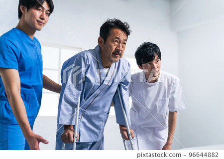 Patient and care staff rehabilitating with crutches 96644882