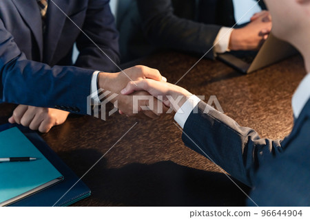 Businessmen shaking hands in a dark office, collusion, corruption, backroom deals 96644904