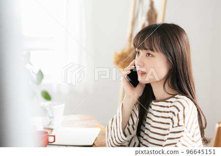 Young woman calling while working from home 96645151