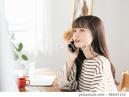 Young woman calling while working from home 96645152