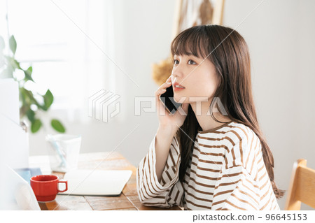 Young woman calling while working from home Young woman calling while working from home 96645153