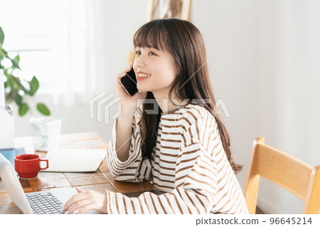 Young woman calling while working from home 96645214