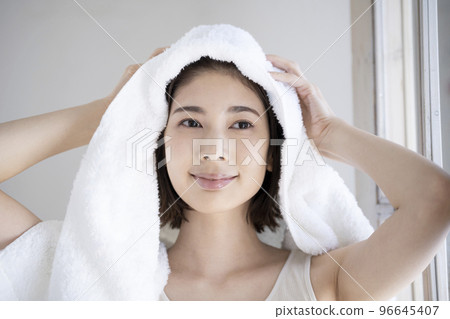 Young woman wiping her hair with a towel 96645407