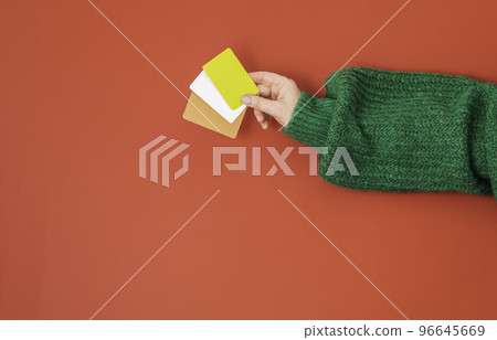 Christmas shopping concept. Flat lie hands in a green sweater with bonus, gift or credit card. Banner on a red background Christmas shopping concept. Flat lie hands in a green sweater with bonus, gift or credit card. Banner on a red background 96645669