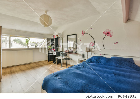 Comfortable bed located near window with curtain in light bedroom with working desk and chair of contemporary flat 96648932