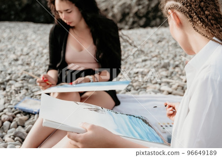 Unrecognizable woman's hands holding her own sea beach scenery watercolor painting. Amateur painter. Creative female artist drawing the picture at the beach. Art, creativity and inspiration concept. Unrecognizable woman's hands holding her own sea beach scenery watercolor painting. Amateur painter. Creative female artist drawing the picture at the beach. Art, creativity and inspiration concept. 96649189