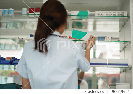 Medicine and health concept, Female pharmacist hold medicine box to checklist in paper at drugstore Medicine and health concept, Female pharmacist hold medicine box to checklist in paper at drugstore 96649665