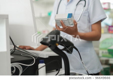 Medicine and health concept, Female pharmacist hold medicine product to working with cash register Medicine and health concept, Female pharmacist hold medicine product to working with cash register 96649666