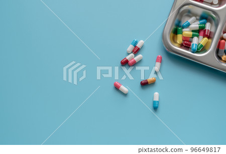 Above view of Colorful antibiotic capsule pills on a tray and blue background. Antibiotic drug resistance. Antimicrobial drugs. Prescription drugs. Pharmaceutical industry. Health care and medicine. Above view of Colorful antibiotic capsule pills on a tray and blue background. Antibiotic drug resistance. Antimicrobial drugs. Prescription drugs. Pharmaceutical industry. Health care and medicine. 96649817