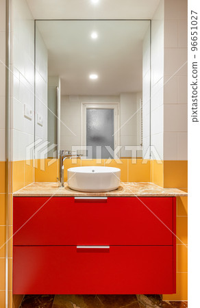 New empty bathroom with yellow tiles and round sink on red furniture 96651027