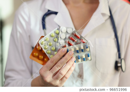 Doctor woman hand holding many blisters with pills closeup 96651996