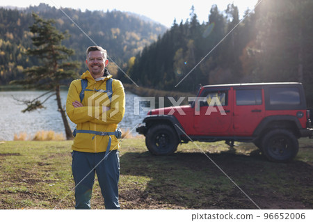 Happy smiling male tourist standing near mountain lake Happy smiling male tourist standing near mountain lake 96652006