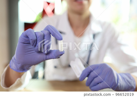 Doctor proctologist holding in his hands antiinflammatory suppository for hemorrhoids closeup 96652019