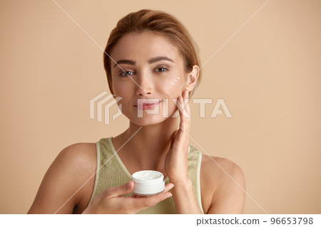 Beauty Woman Applying Face Cream. Closeup Of Female Model Holding Cream Bottle 96653798