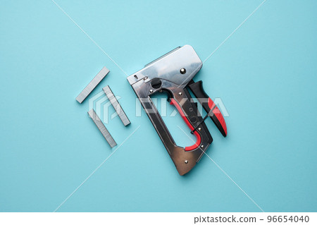 Household manual stapler and staples on a blue background, top view 96654040