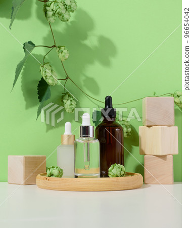 Glass bottles with pipettes for liquid cosmetics on a wooden stand 96654042