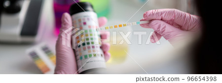 Clever scientist hold litmus test paper for soil analysis, papers show acidity Clever scientist hold litmus test paper for soil analysis, papers show acidity 96654398