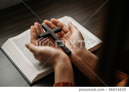 Woman sitting and studying the scriptures.The wooden cross in the hands. Christian education concepts The Holy Scriptures open Woman sitting and studying the scriptures.The wooden cross in the hands. Christian education concepts The Holy Scriptures open 96654830