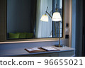 The desk in the room had a lamp on the table. There is a mirror on the back. 96655021