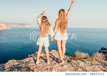 Sea family vacation together, happy mom and teenage daughter hugging and smiling together over sunset sea view. Beautiful woman with long hair relaxing with her child. Concept of happy friendly family Sea family vacation together, happy mom and teenage daughter hugging and smiling together over sunset sea view. Beautiful woman with long hair relaxing with her child. Concept of happy friendly family 96655312