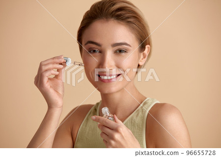 Woman Applying Serum on Face. Woman Applying Essential Oil On Facial Skin Woman Applying Serum on Face. Woman Applying Essential Oil On Facial Skin 96655728