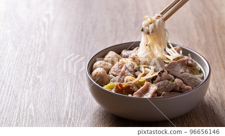 Rice noodles soup with pork in bowl eating by chopsticks on wooden background, Asian food 96656146