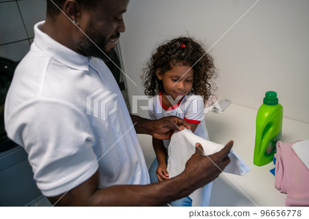 Little girl and her parent at the laundromat 96656778
