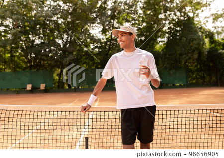 Young man in white thsirt standing at the tennis court 96656905